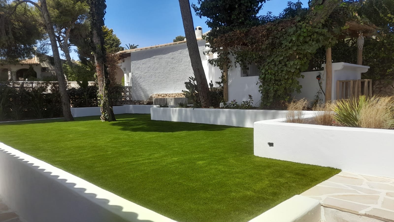Villa garden with white raised planters and artificial grass Spain