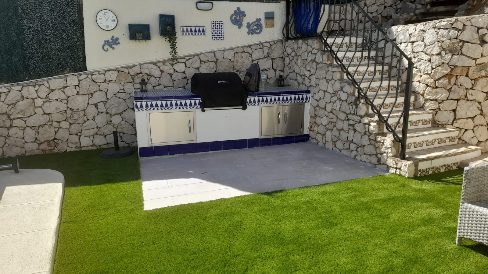 Artificial grass terrace with outdoor kitchen stone wall Spain